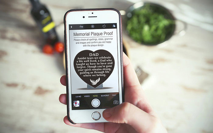 Person holding phone looking at a memorial plaque proof