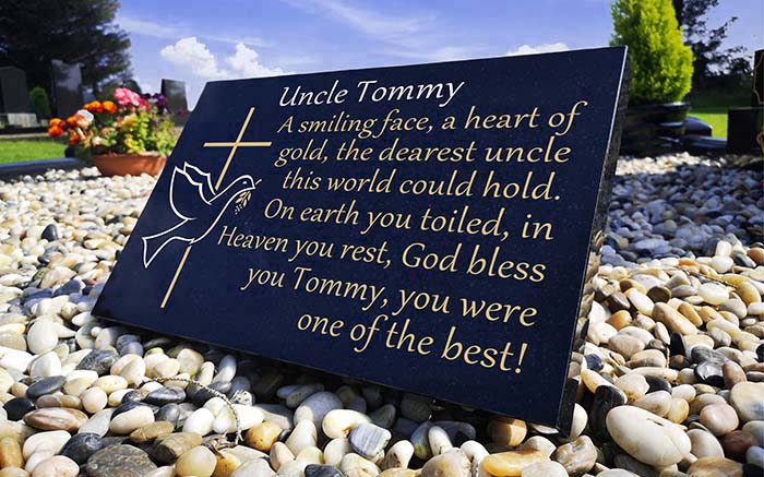 Remembrance plaque on grave with dove and cross engraved